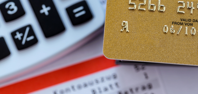 a gold credit card, bank statement and calculator. symbolic photo for cashless transactions and status symbols.